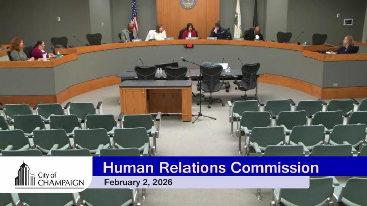 Wide shot of Dias with five commissioners seated facing an empty audience. 