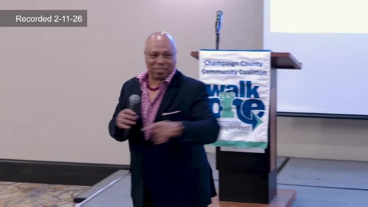 Tracy Parsons at front of room in front of Walk as One banner. 